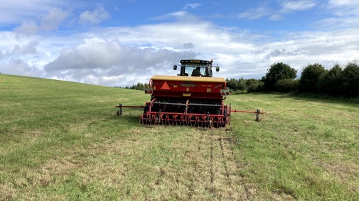 Rear view of tractor in farmer's field in autumn with seed drilling equipment in use